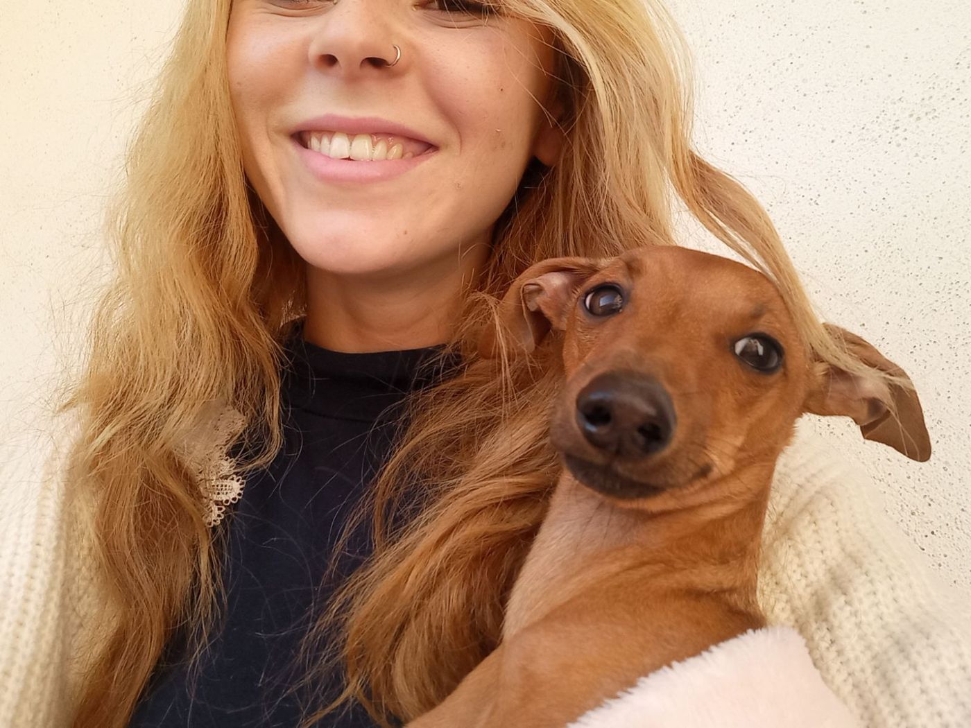 Lana se smiješi sa smeđim psom u naručju.
